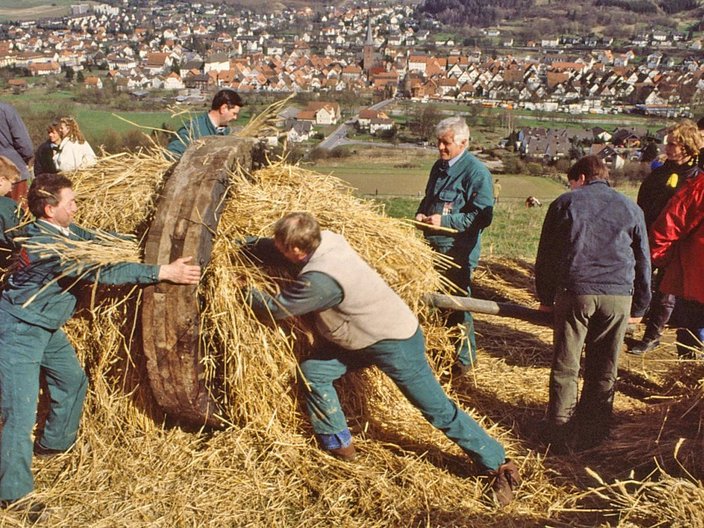 Männer stopfen Stroh in ein Holzrad