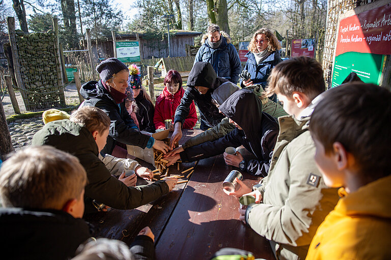 Auf diesem Foto ist eine Schulklasse zu erkennen, die bei einem Besuch des Tierparks an interaktiven Projekten teilnimmt