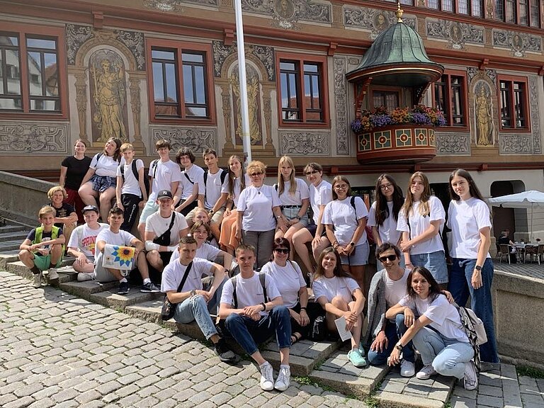 Die Gruppe steht und sitz f&uuml;r ein Foto auf der Br&uuml;cke vor dem Rathaus in T&uuml;bingen.