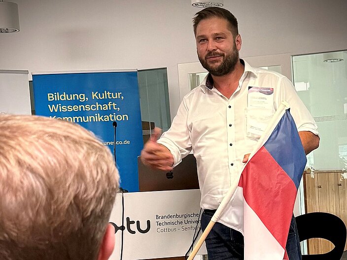 Ein Sorbe mit der sorbischen Fahne in der Hand spricht zum Publikum