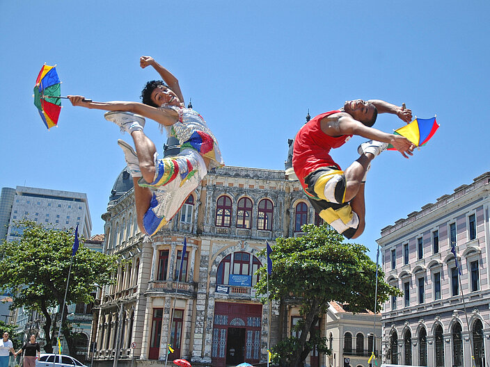 Zwei Tänzer springen beim Frevo in Recife in Brasilien in die Luft