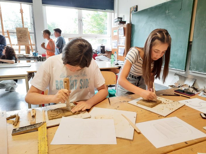 Zwei Schülerinnen sitzen in einer Klasse am Tisch und töpfern.