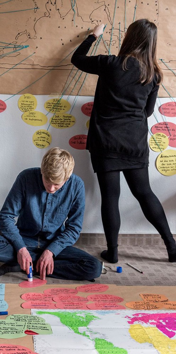 Junge Menschen arbeiten gemeinsam an einer Weltkarte.
