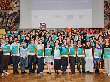 Die Gruppe von 31 Ausgezeichneten stehen gemeinsam vor der B&uuml;hne