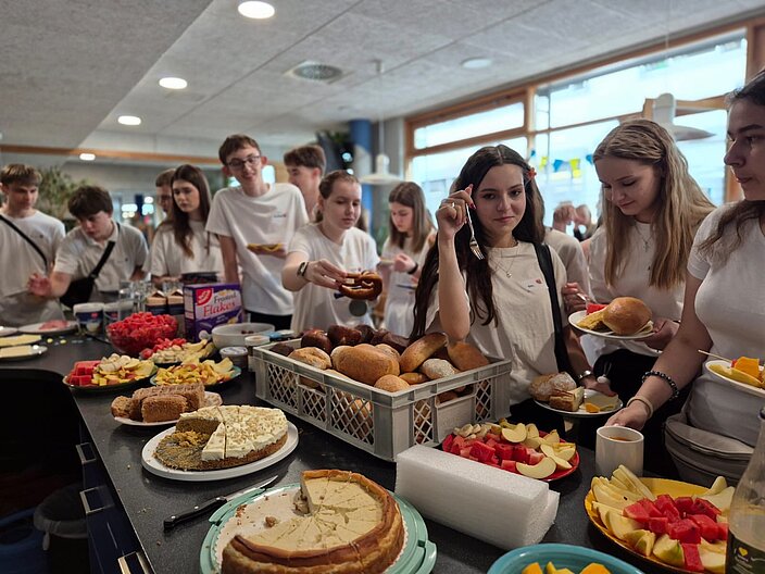 Jugendliche die sich beim Willkommensfest an einem Buffet bedienen