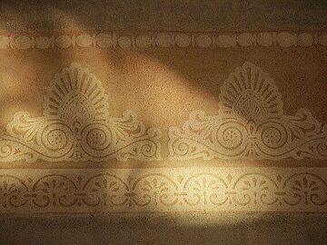 Detail einer mit ornamentalen Mustern gestalteten Kalkm&ouml;rtel-Oberfl&auml;che.