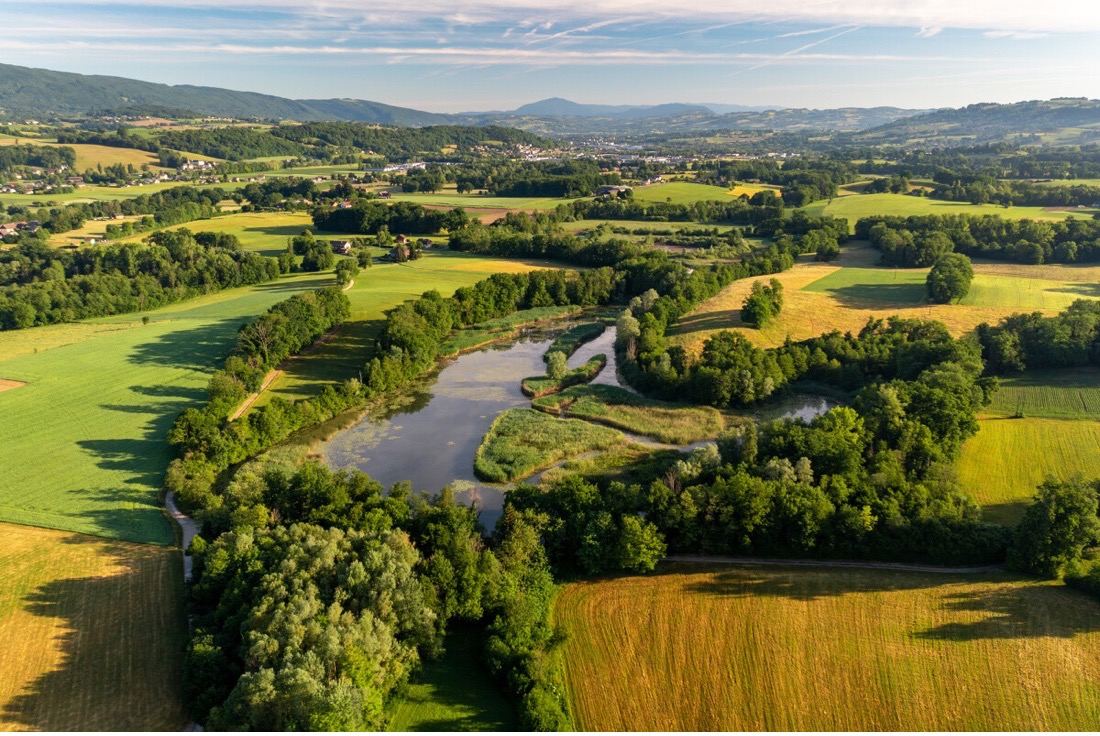 Ein sonniges Tal aus Flüssen, Bäumen und Feldern