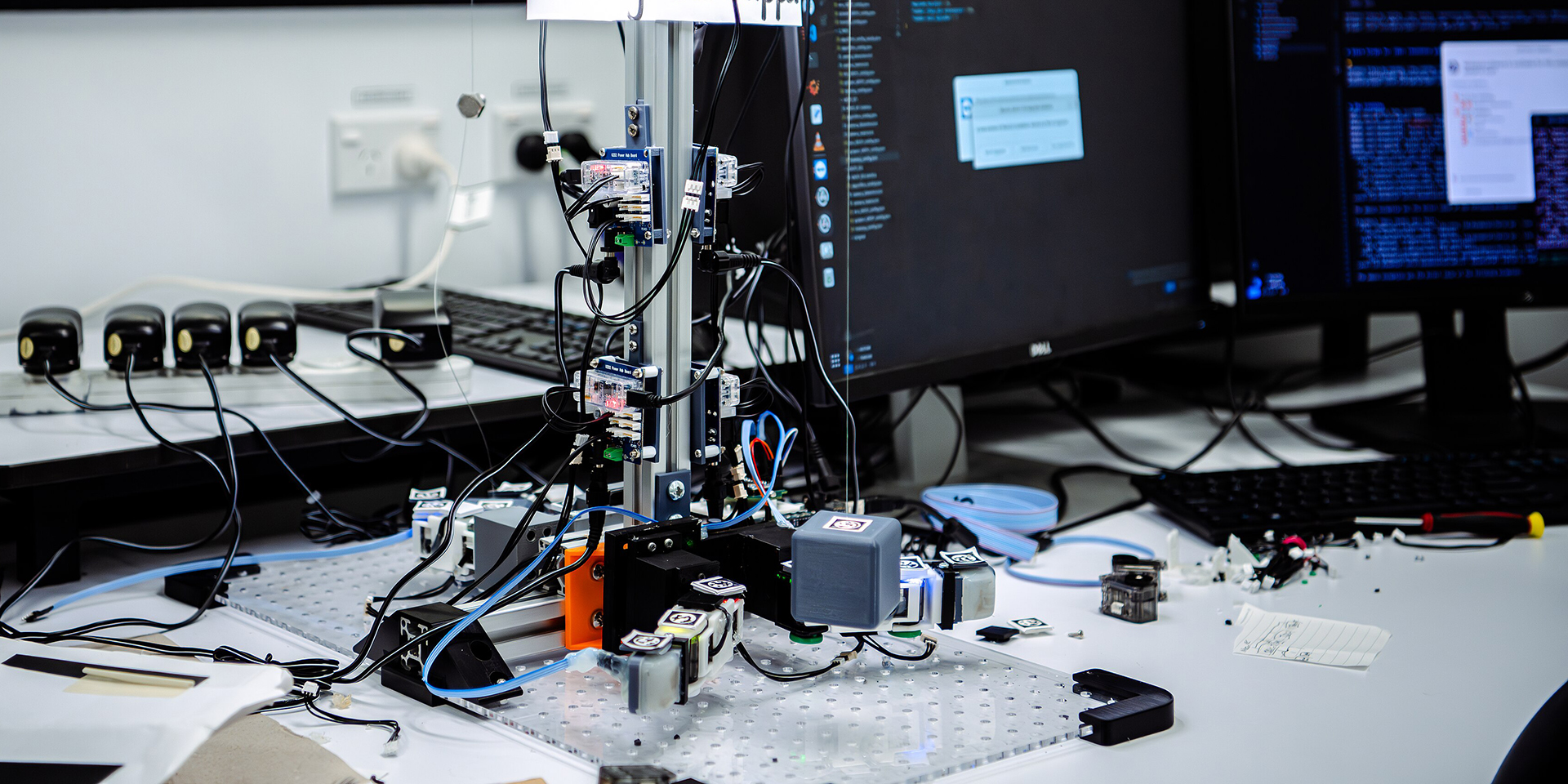 Robotik Schreibtisch mit verschiedenen wissenschaftlichen Geräten und Computerbildschirmen, die einen Robotik-Aufbau zeigen