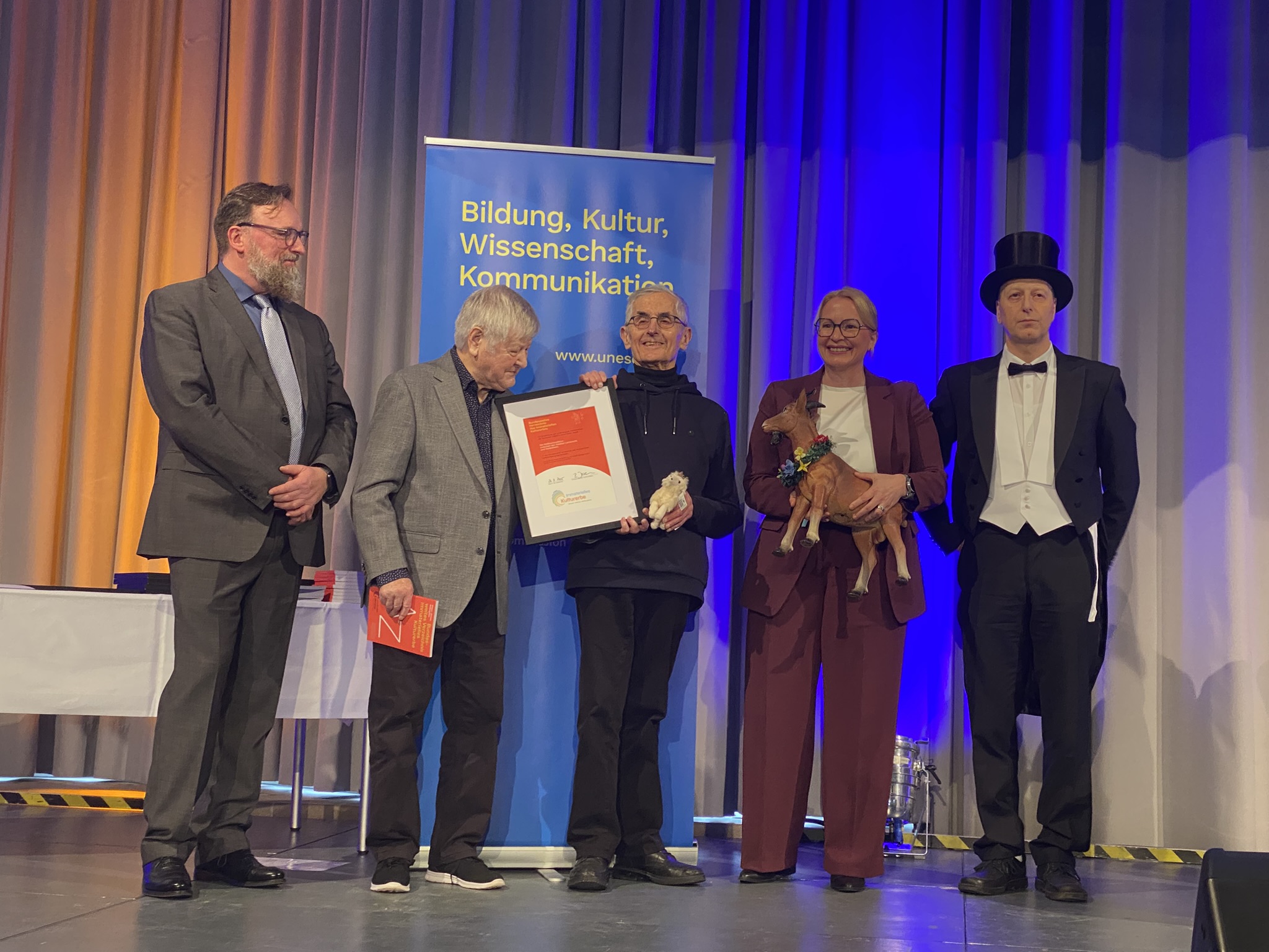 fünf Personen auf der Bühne beim bundesweiten Festakt Immaterielles Kulturerbe 2025 im Schloss Saarbrücken