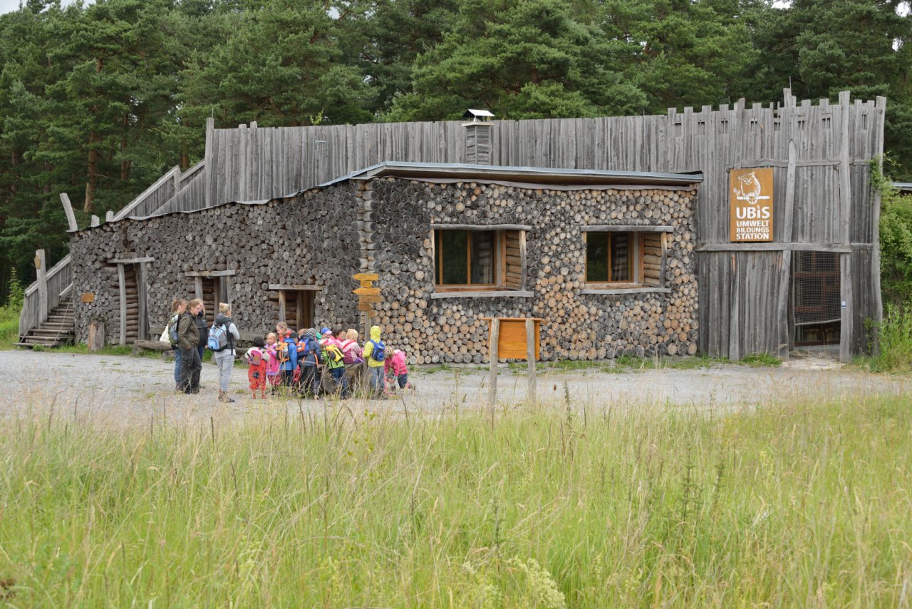 Eine Kindergruppe vor der Umweltbildungsstation, die aus Holz gebaut wurde.