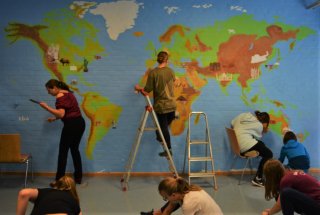 Schüler malen auf eine Wand die Weltkarte