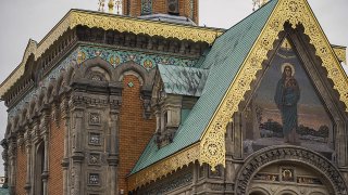 Nahaufnahme der Fassade einer russisch-orthodoxen Kirche mit ornamentalen Fliesen und goldenen Verzierungen.