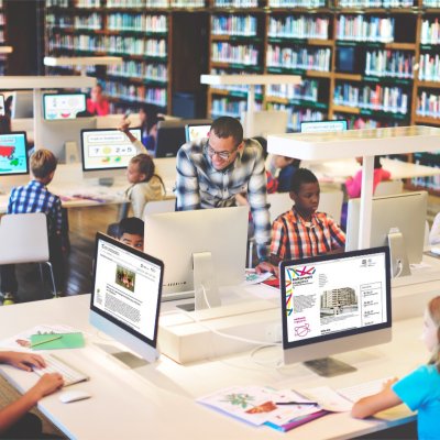 Kinder sitzen in einer Bibliothek an Computern