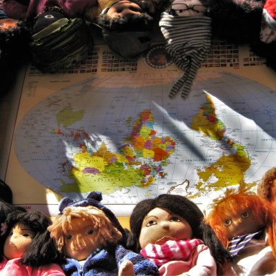 Verschiedene Puppen sind um eine Weltkarte herum angeordnet 
