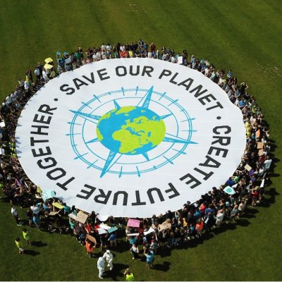 Schüler platzieren sich um ein rundes Banner auf dem u.a. "Save our Planet" steht