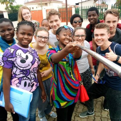 Eine international durchmischte Gruppe Jugendlicher macht ein gemeinsames Selfie