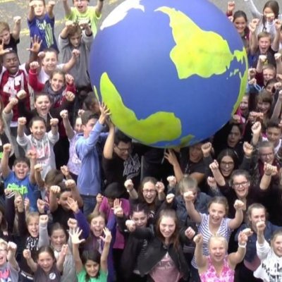 Schüler der Primarstufe balancieren einen großen Ball in Form und Farbe der Erde